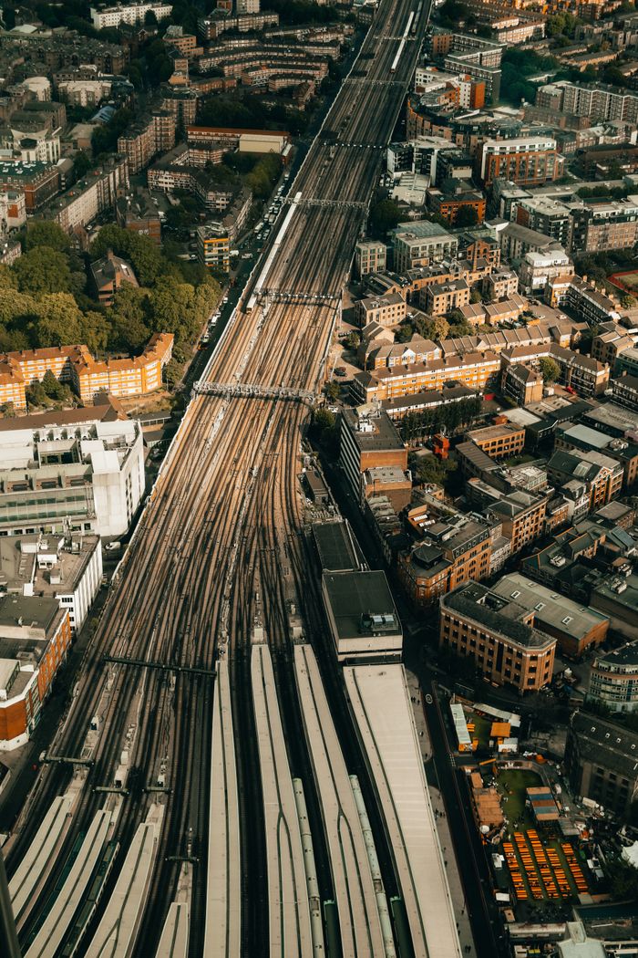 Aerial shot showcasing an urban railway station and surrounding cityscape with complex train tracks.